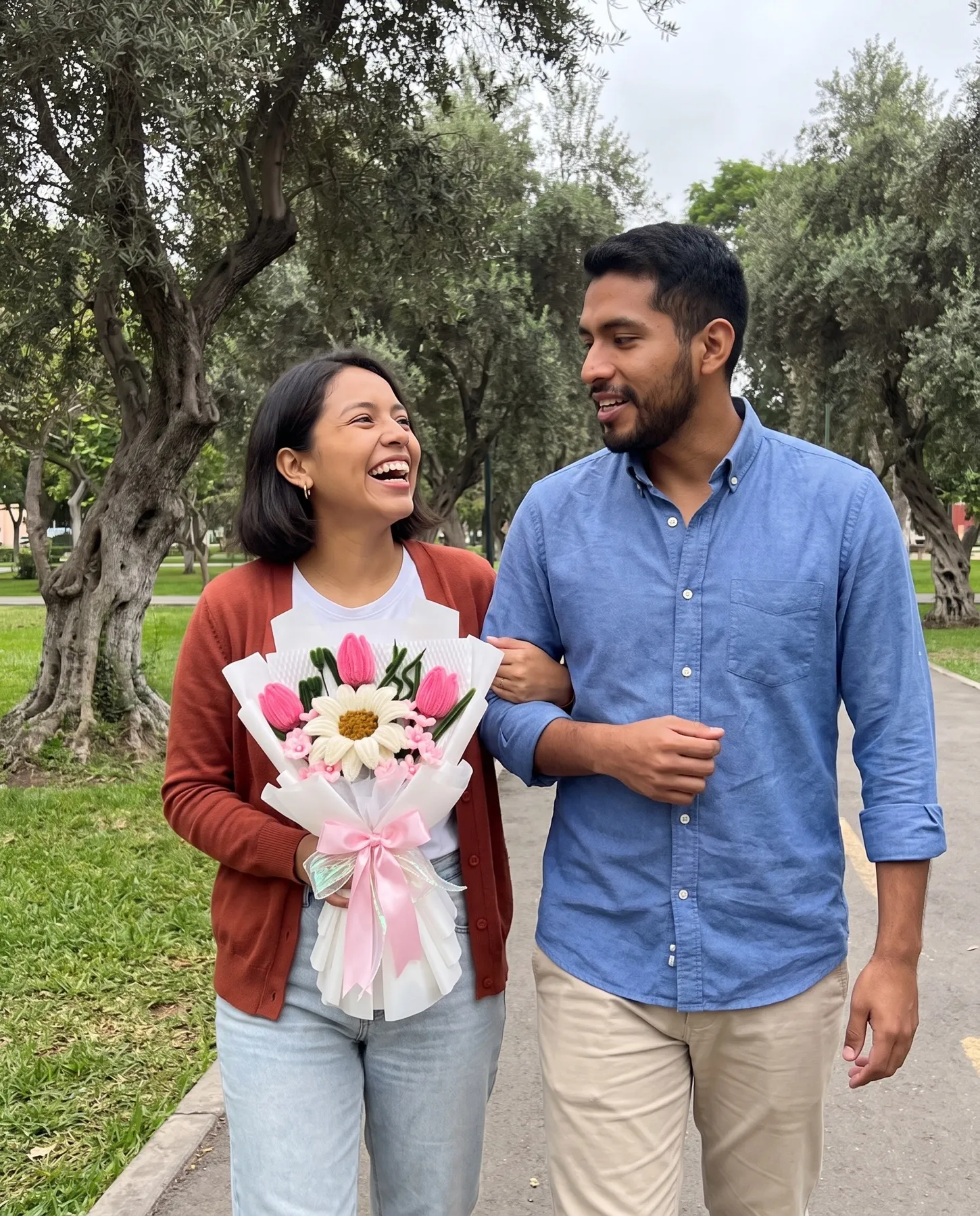 Una pareja camina del brazo por el parque; ella lleva un ramo